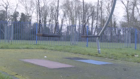 still swing on children playground with no people on a cloudy cold day in central london