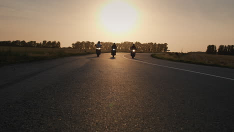 three bikers drive along the highway past the camera