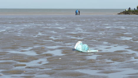 Blaue-Gebrauchte-Chirurgische-Gesichtsmaske,-Die-Achtlos-Am-Sandstrand-Aus-Nächster-Nähe-Geworfen-Wurde