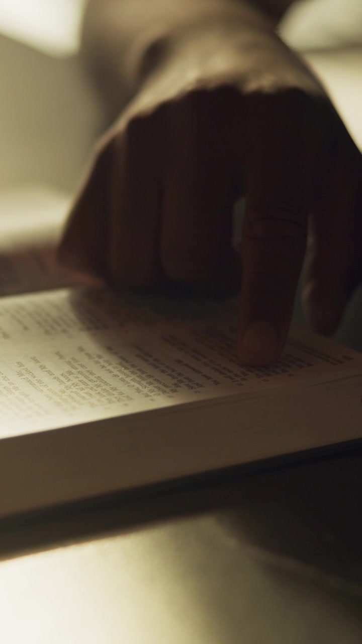 Person Reading a Book with Finger Pointing at Text