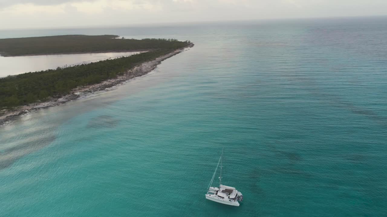 vista aérea de drones de la isla desierta de las bahamas con un velero solitario al amanecer