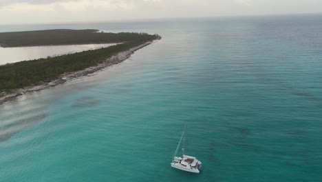 Vista-Aérea-De-Drones-De-La-Isla-Desierta-De-Bahamas-Con-Un-Velero-Solitario-Al-Amanecer