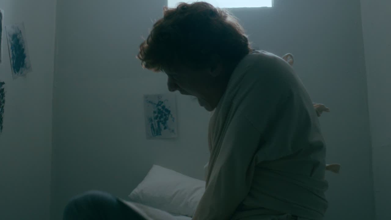 Man with Mental Disorder Struggling to Escape Straitjacket in White Room