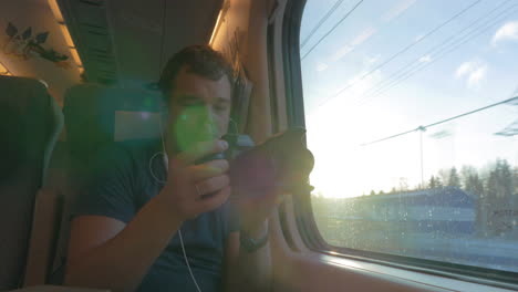 hombre en el tren filmando y mirando por la ventana