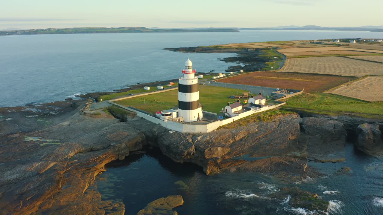 조감도, 일출, 날아가는 샷, 후크 등대는 12세기에 지어진 세계에서 가장 오래된 등대인 아일랜드 co wexford의 후크 반도 끝에 있는 후크 헤드에 있습니다.