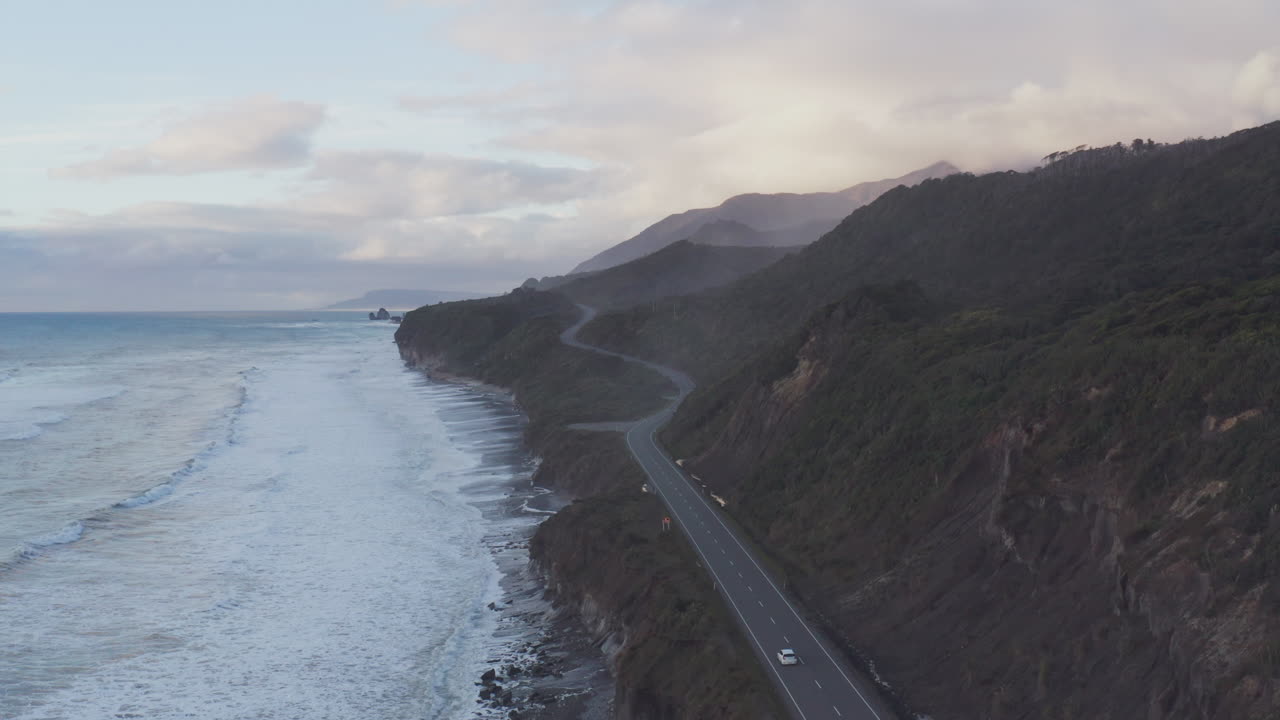 un coche conduce a lo largo de la autopista en la costa oeste de la isla sur de nueva zelanda