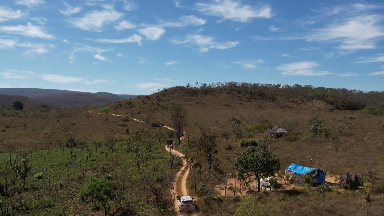 vista drone di un'auto in movimento che solleva polvere su una strada sterrata nella Chapada dos Veadeiros, Goiás, Brasile