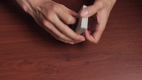 Close-up-of-hands-shuffling-a-deck-of-cards-on-a-table