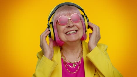 Senior-woman-listening-music-on-headphones-dancing-disco-fooling,-having-fun,-gesticulating-hands