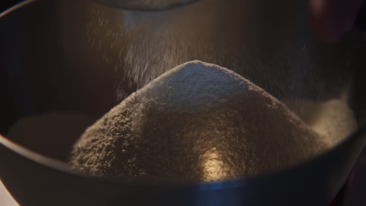 Close-up van het zeven van witte bloem in een metalen kom
