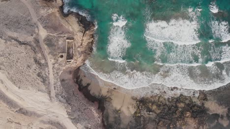 An-abandoned-house-with-a-limestone-oven-for-calcination-on-the-shoreline-with-turquoise-waves