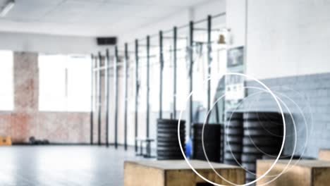 Animation-of-white-circles-spinning-over-industrial-gym-interiors