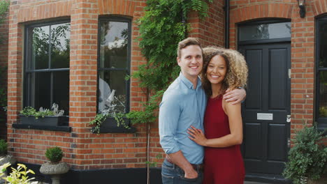 Portrait-Of-Excited-Young-Couple-Standing-Outside-New-Home-Together