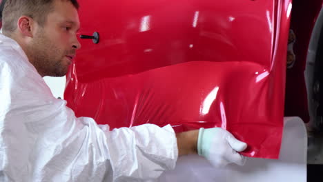 la aplicación de envoltura de vinilo rojo a una puerta de coche