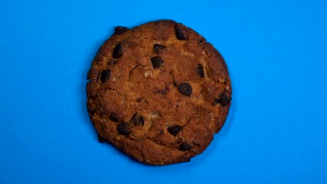 una galleta de chocolate en primer plano, una foto macro, girando rápidamente sobre un fondo azul giratorio.