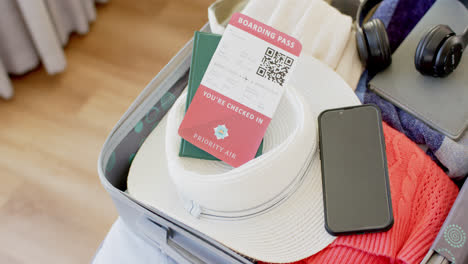 close up of luggage with a ticket, passport, smartphone and headphones in suitcase