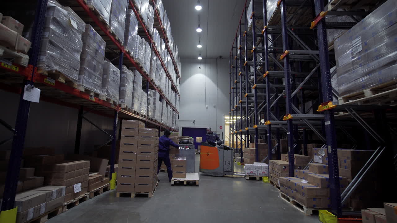 trabajadores de almacén que manejan paletas y cajas en una instalación de almacenamiento en frío