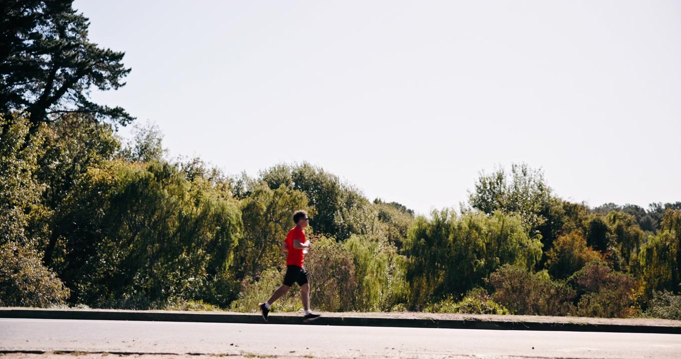 Man Jogging on Roadside Path Near Trees