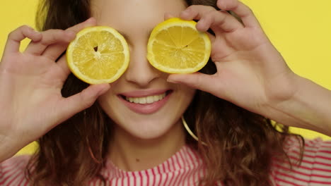 Young-woman-kissing-lips-with-lemon-slices-in-front-of-eyes