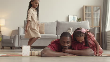 kids jumping over father lying on floor