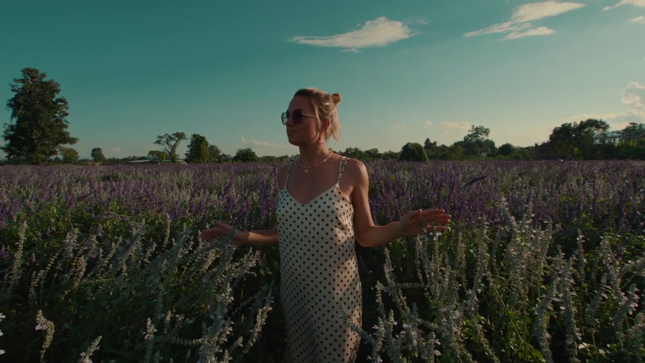 Giovane donna che cammina attraverso un campo fiorito di fiori viola