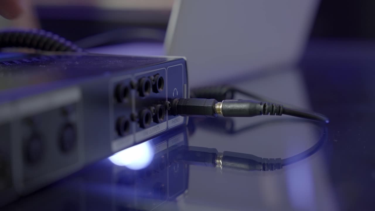 cerca del adaptador de auriculares de un cuarto de pulgada en el puerto de audio, con la mano caucásica conectando el mini cable de auriculares en el puerto del adaptador de un cuarto de pulgada