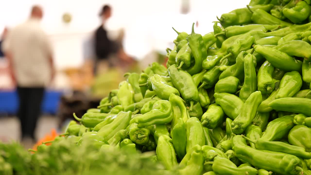una pila de pimientos verdes en un mercado de agricultores