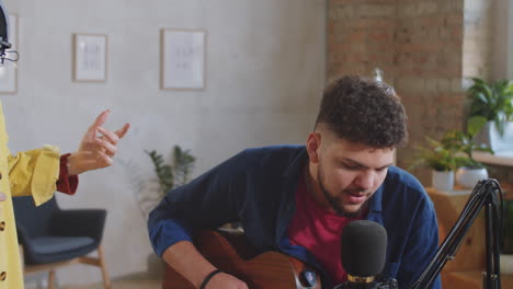 músicos masculinos y femeninos cantando y tocando la guitarra en el estudio de grabación