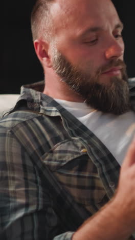 caring woman brings water and pills to husband suffering from cardiac problems. upset bearded man lies on sofa at home putting hand on chest closeup