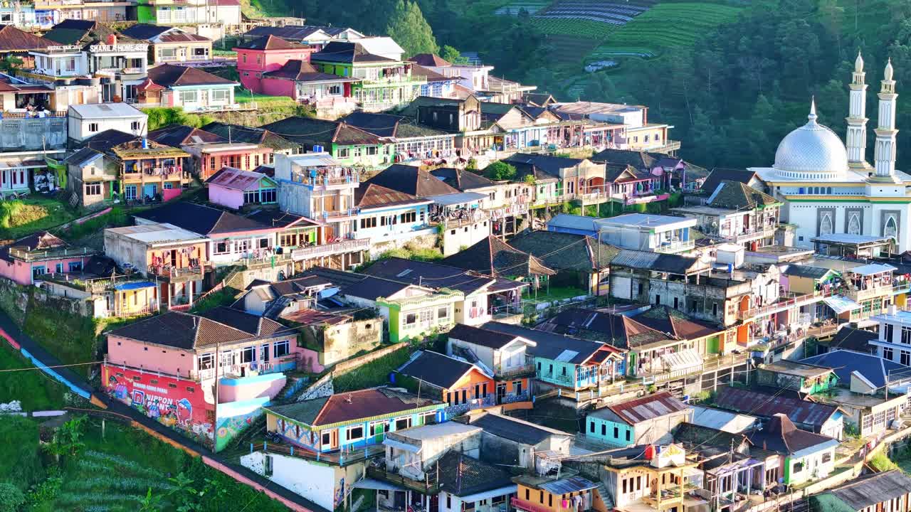 Aerial view of a picturesque Indonesian highland village with colorful houses, a mosque, and terraced fields on a sunny day. Nepal Van Java, Mount Sumbing