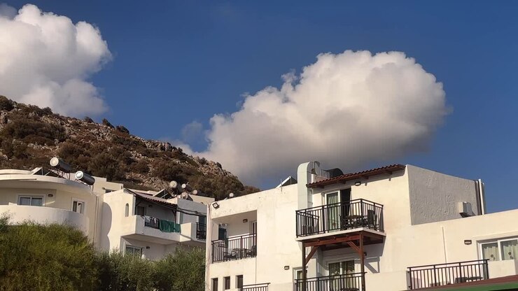Whitewashed houses near a mountain in Crete, Greece, under a vibrant sky