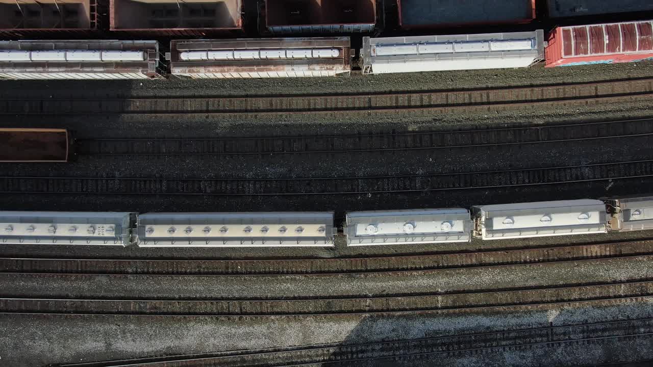 Railroad track and rail cars at switching station, topdown rising aerial birds eye view, railroad transportation theme