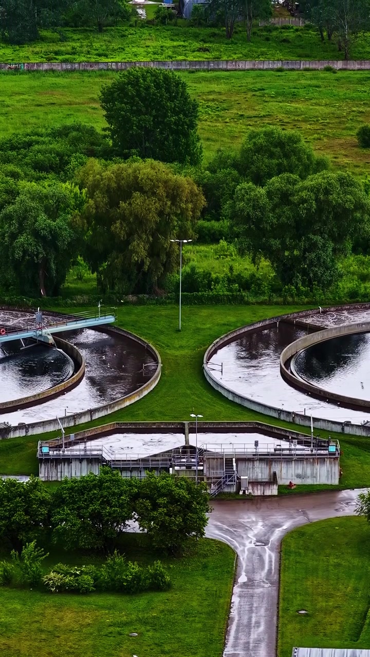 Circular Clarifier Basins and Treatment Infrastructure are Surrounded by Green Landscapes as Part of a Sewage and Water Purification Process Viewed from Above - Aerial Ascend Shot
