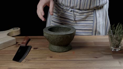 front view of the cook putting oregano in a mortar to crush it and pour it into the chimichurri jar