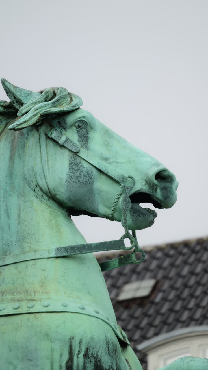 Statua in bronzo del vescovo Absalon che sorregge un pastorale, con l'orologio del municipio di Copenaghen sullo sfondo