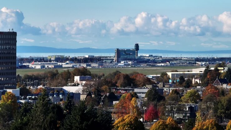 Aereo in arrivo atterra all'Aeroporto Internazionale di Vancouver con vista sulla Torre di controllo e sulla stazione della metropolitana YVR.