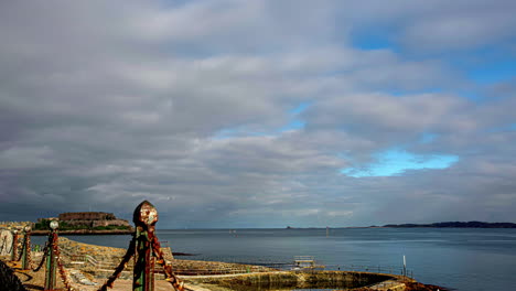 Vista-Lejana-Del-Castillo-Corneta-Desde-La-Piscina-Costera-En-El-Puerto-De-San-Pedro,-Guernsey