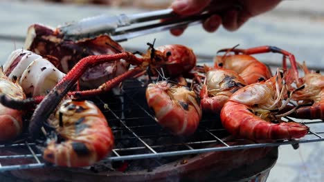 Una-Vista-Lateral-De-Gambas-Gigantes-De-Río-Friéndose-En-La-Barbacoa-Y-Siendo-Girada-Por-Una-Chica-Tailandesa