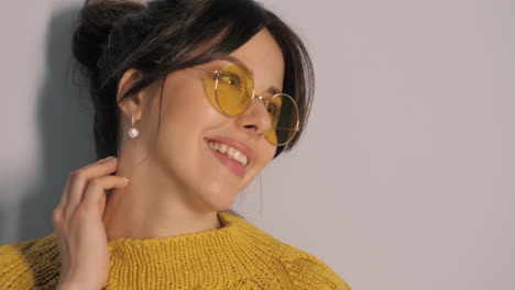 mujer sonriente con suéter amarillo y gafas de sol