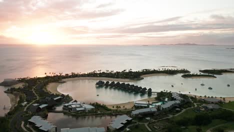 resort de fiji en la costa continental durante la brillante puesta de sol con bungalows sobre el agua