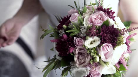 Bride-in-white-dress-holding-a-wedding-bouquet-with-one-hand,-close-up-view