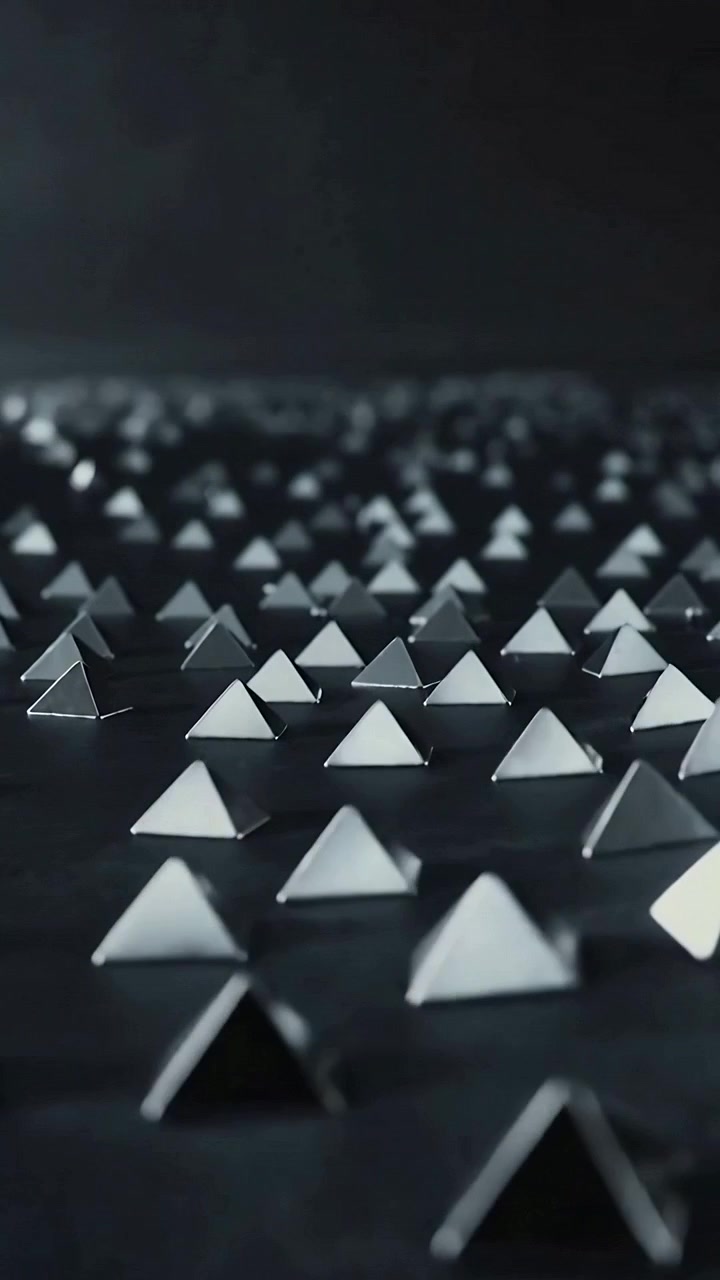 Video verticale: Movimento di dolly con messa a fuoco a rack lungo una piattaforma scura che mostra geometrie piramidali e perline