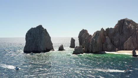 slide aerial of rock formation in pacific ocean revealing view on natural arch, landmark of cabo san lucas mexico