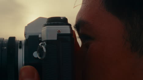 a man taking a photograph with a vintage camera at sunset