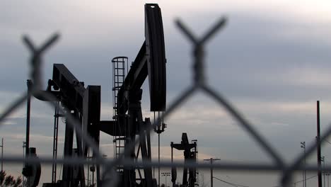 Oil-pump-in-Los-Angeles-behind-barb-wire,-Los-Angeles,-USA