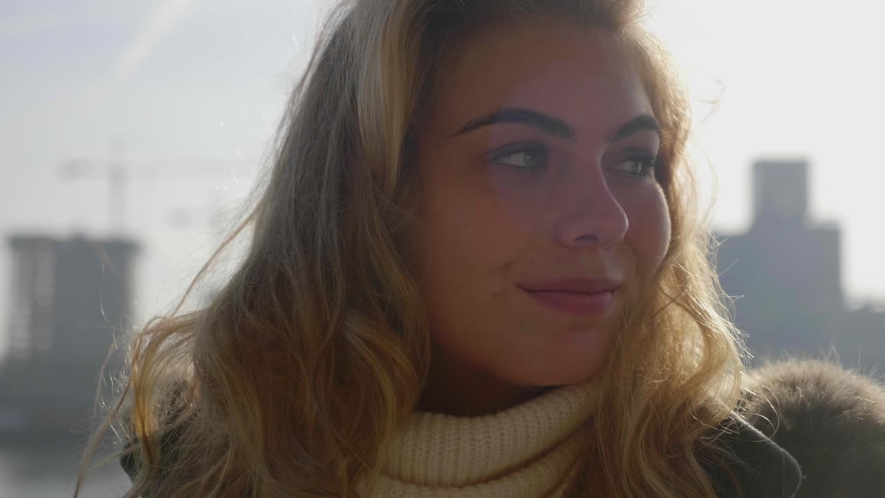 Primo piano di una giovane donna introspettiva, che pensa e sorride.