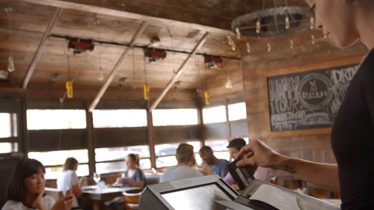 젊은 여성 이 레스토랑 에서 청구서 를 지불 하기 위해 카드 를 사용 한다