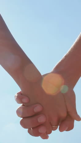 un primer plano de una pareja tomándose de la mano en la playa