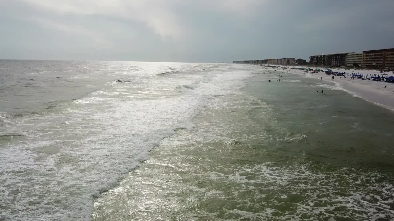 거품이 이는 파도가 있는 아름다운 바다가 해질녘에 모래사장에서 구르고 충돌합니다 - 공중 드론 샷