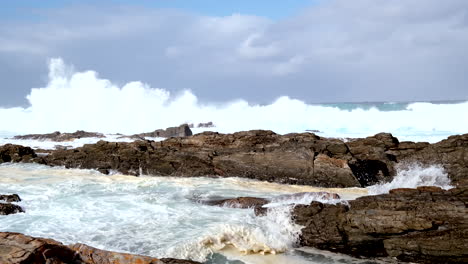 foaming breakers crash over shallow rugged reef at storms river mouth. slomo